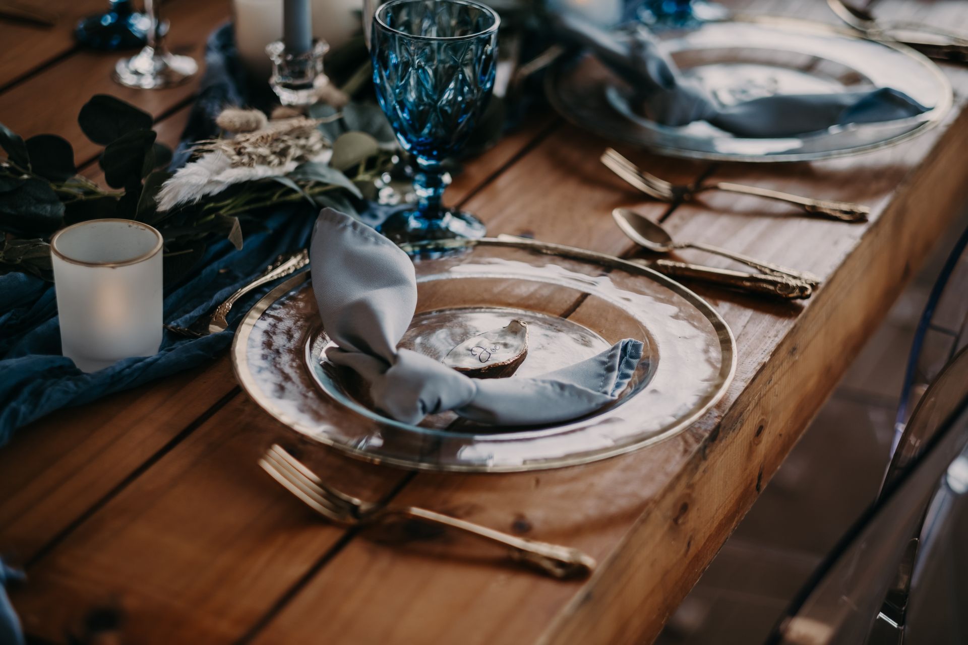 Luxurious dinner table setting featuring blue glassware and gold cutlery, creating an elegant atmosphere.