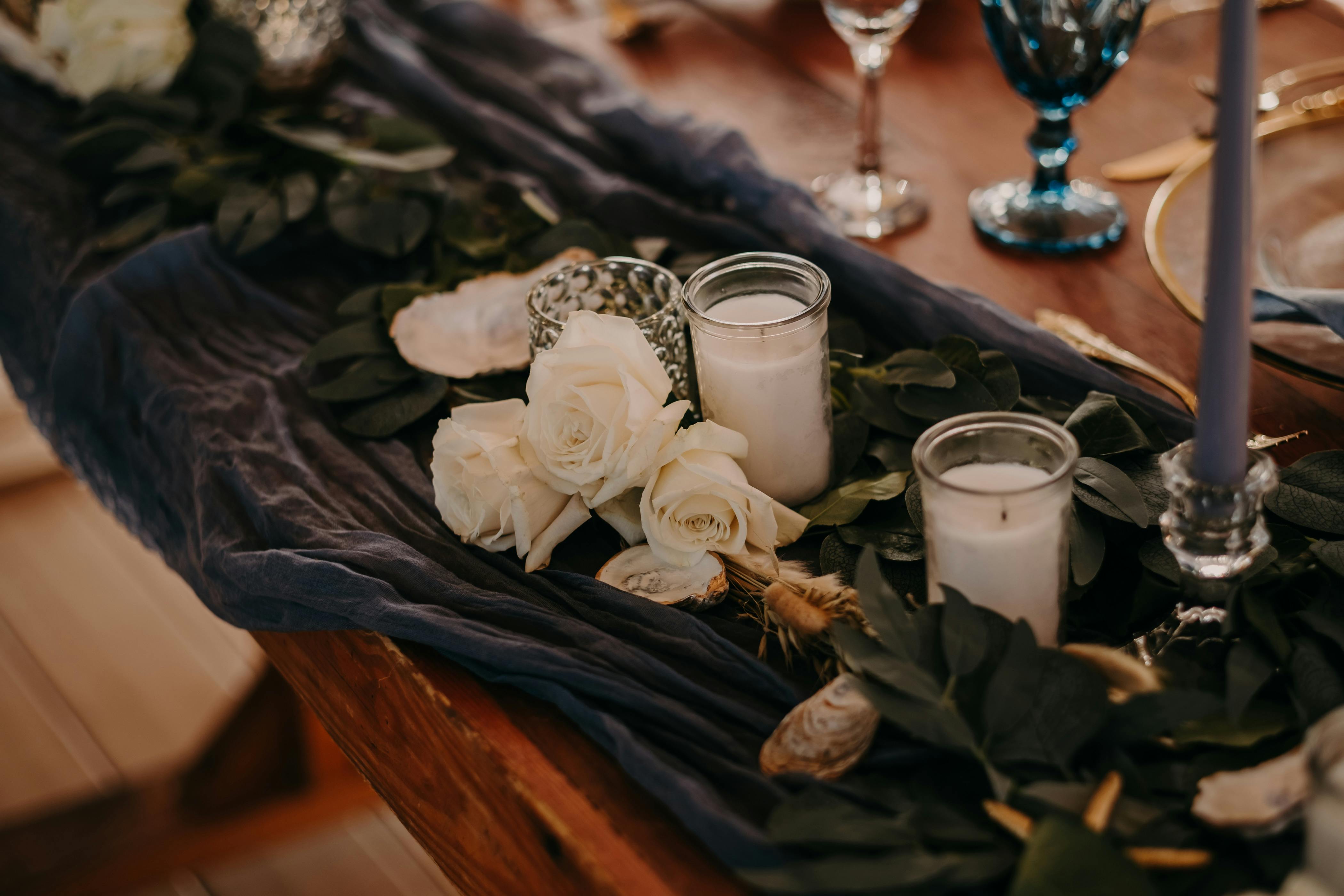 A beautifully decorated table with white candles, roses, and leaves. Perfect for celebrations.