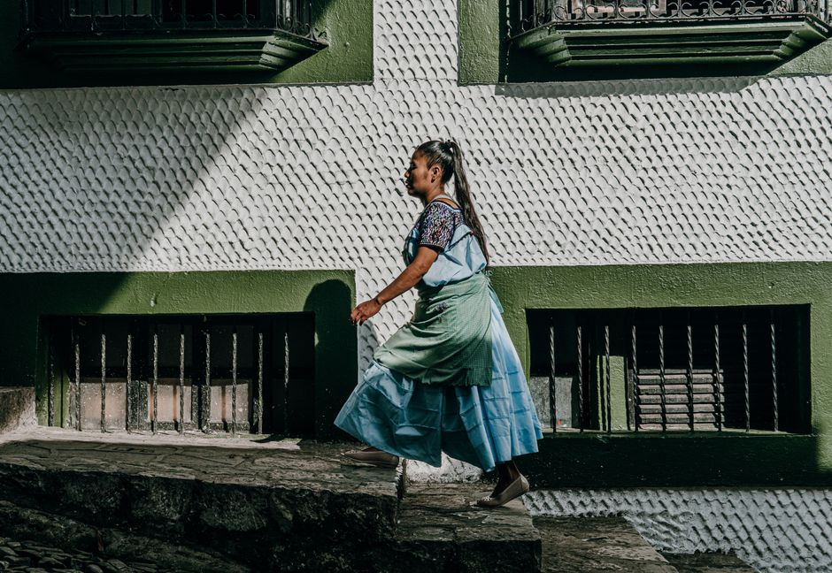 A woman walks in Ciudad de Cuetzalan wearing traditional clothes, showcasing cultural heritage.