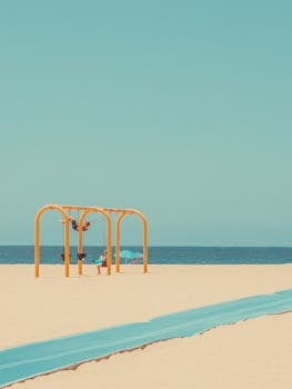 Kids enjoy a sunny day playing on swings at Hermosa Beach with clear blue skies.