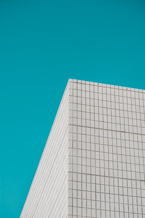 Free A sleek modern building facade with a geometric pattern set against a clear blue sky. Stock Photo