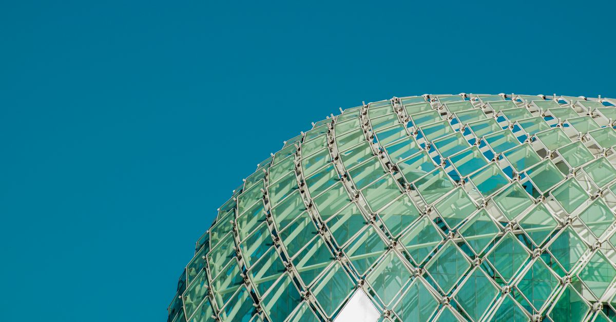 Dome structure with glass panels against clear blue sky in Abu Dhabi.