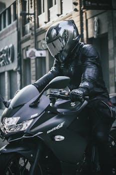 A man in a helmet poses on a modern motorbike in an urban environment.