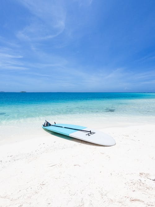 Blue Seascape and Surfboard on Sand