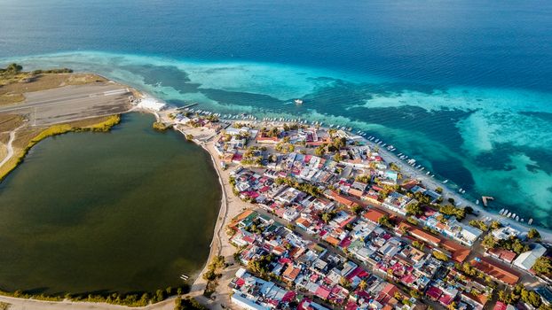 Colorful coastal town on a Caribbean island with turquoise waters and vibrant buildings.