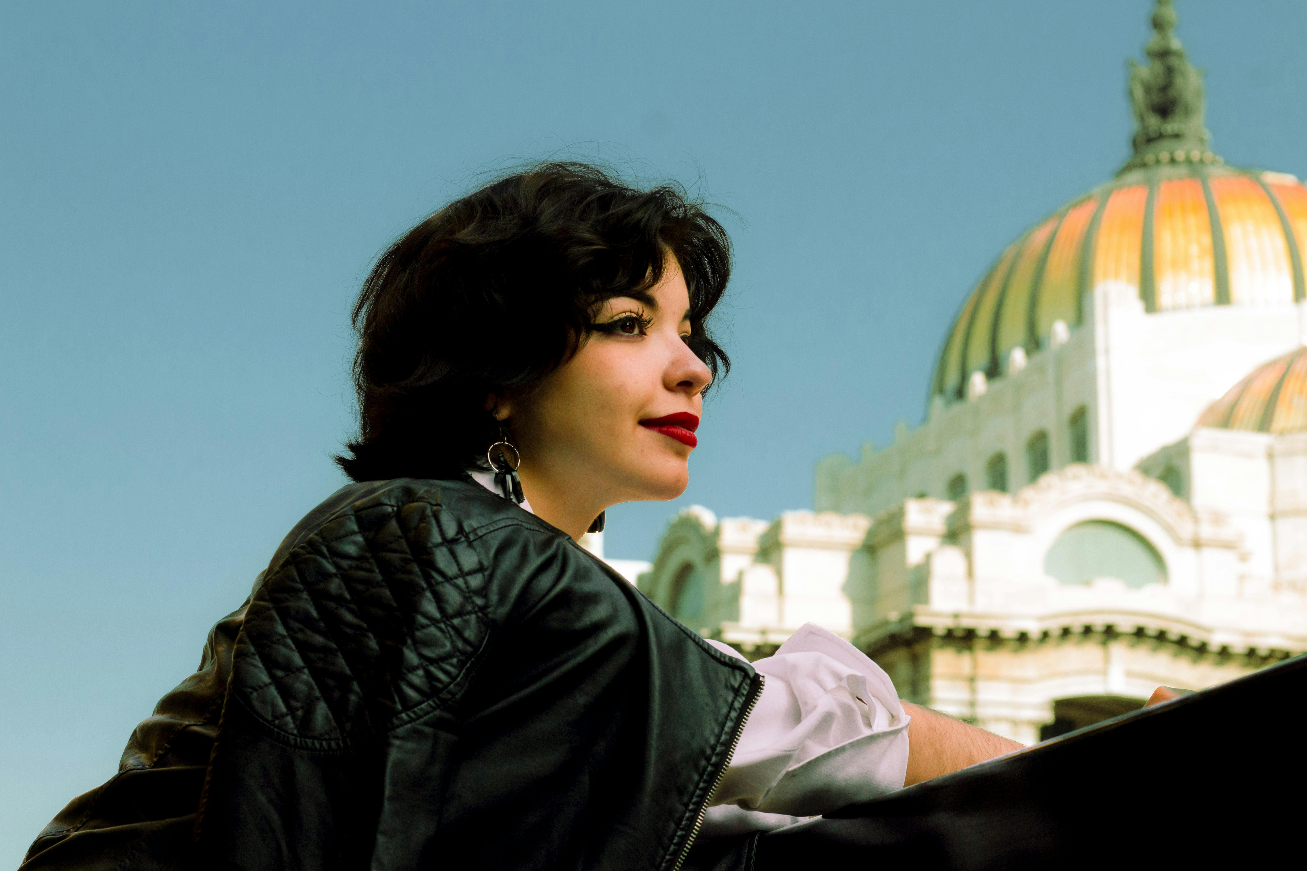 smiling woman in a leather jacket with the palacio de bellas artes in the background
