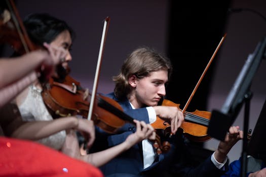 Classical musicians focused on playing violins during a live performance.