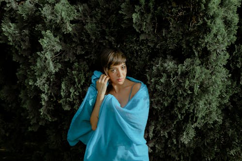 Woman in Blue  Dress Standing Near a Evergreen Tree