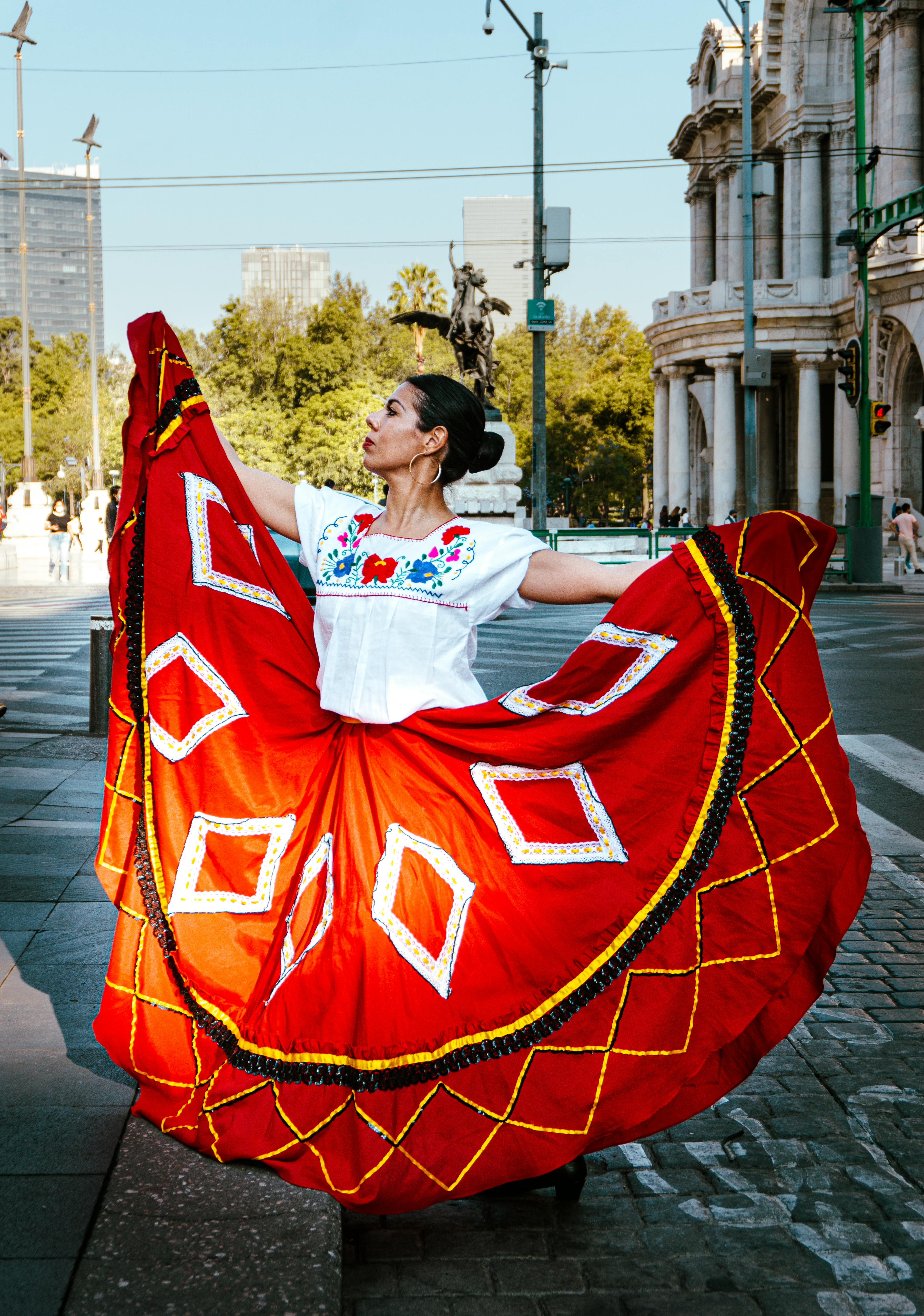 A woman in traditional folkloric dress dancing in the streets of Mexico City.