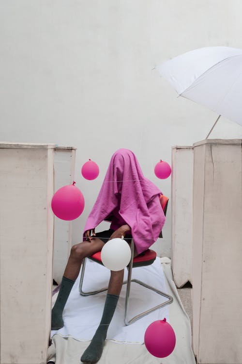Man with Pink Sheet on Head Sitting on Chair 