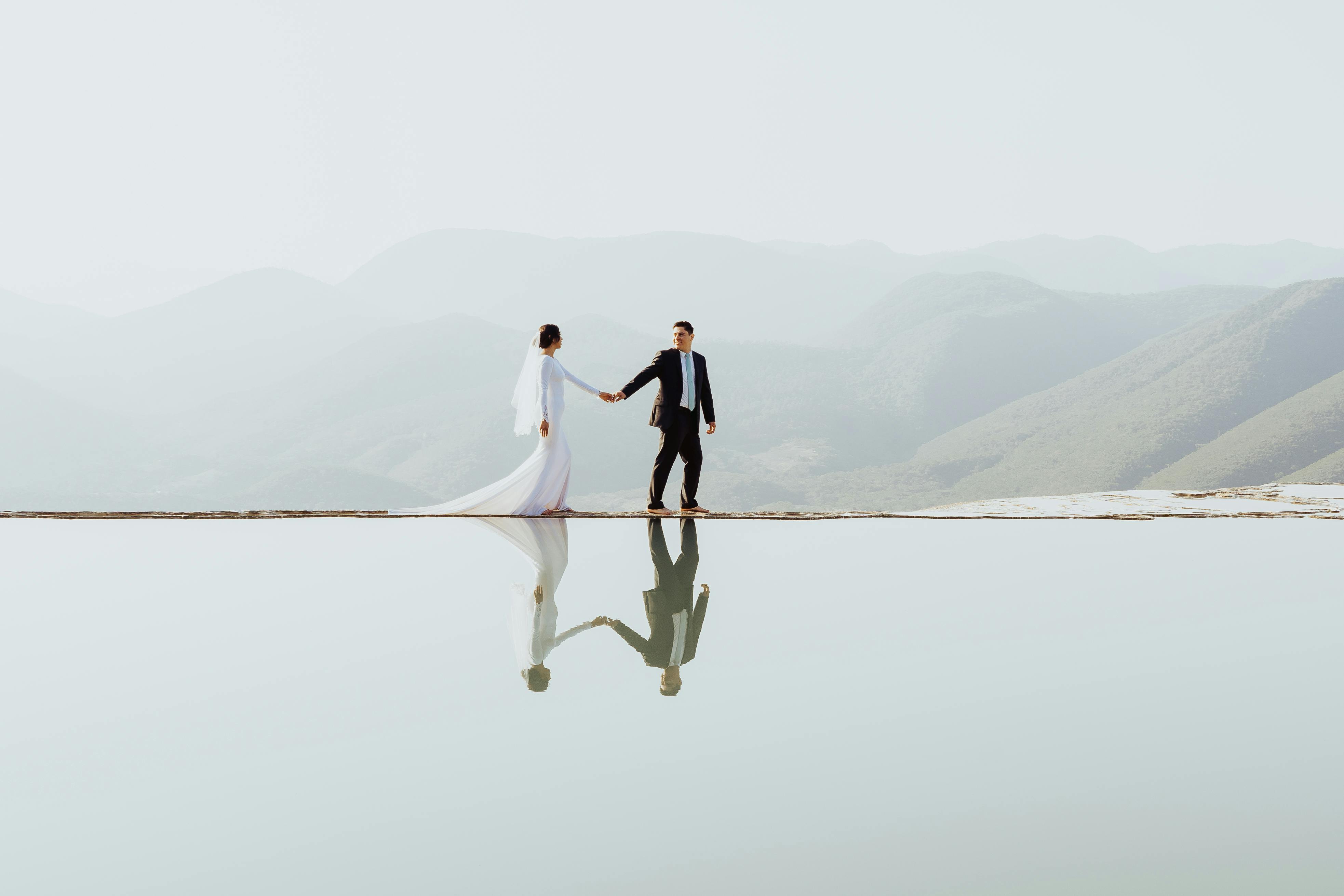 Stunning wedding image with couple by reflective water at Oaxaca, blending elegance and nature.