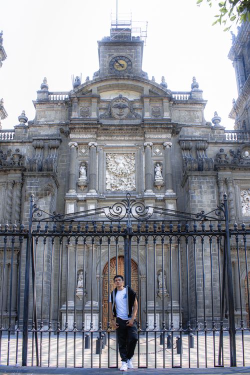 Free A man posing in front of an ornate historical building with a wrought iron gate. Stock Photo