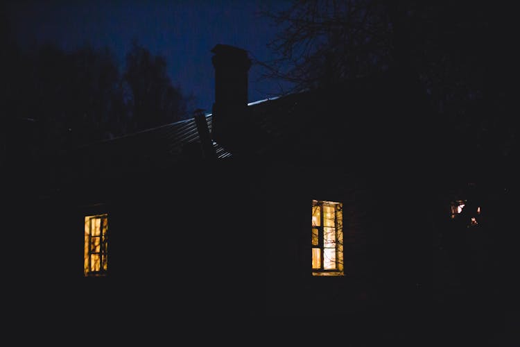 Rural House With Light Seeping From Windows At Night