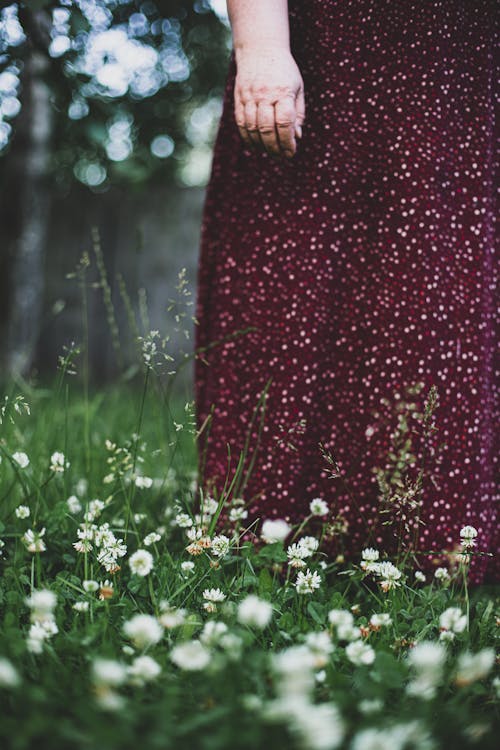 A Person in Red and White Polka Dot Dress Standing on Green Grass Field