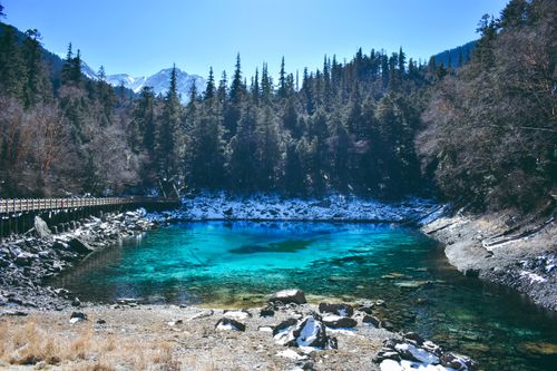 Free A beautiful mountain lake surrounded by a winter forest and snowy mountains. Stock Photo