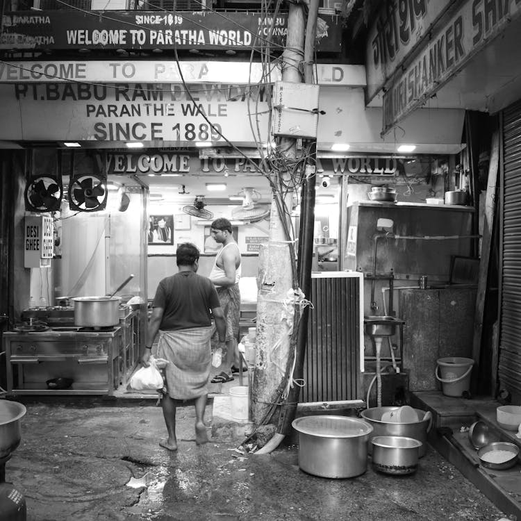 Black And White Photo Of Two Men In Chandni Chowk Market Of Delhi, Old Delhi Street, India 