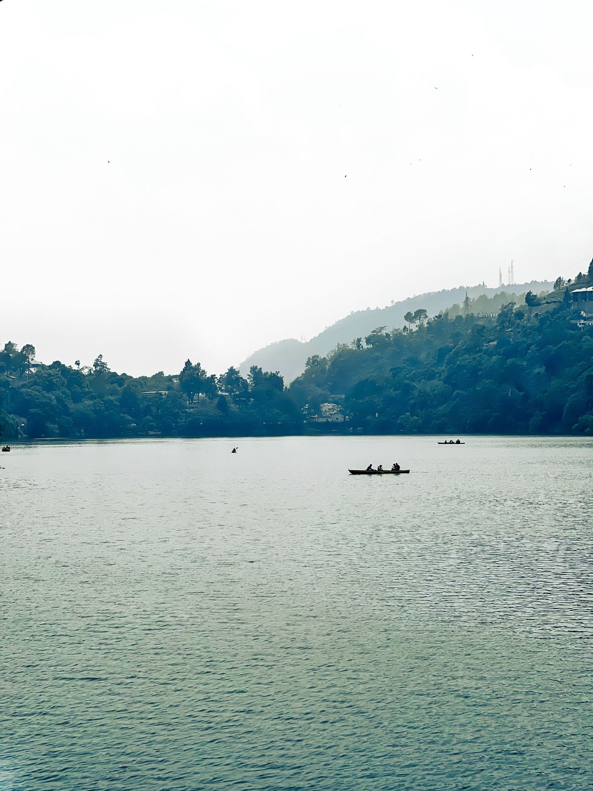 Serene view of Bhimtal Lake with small boats and surrounding hills