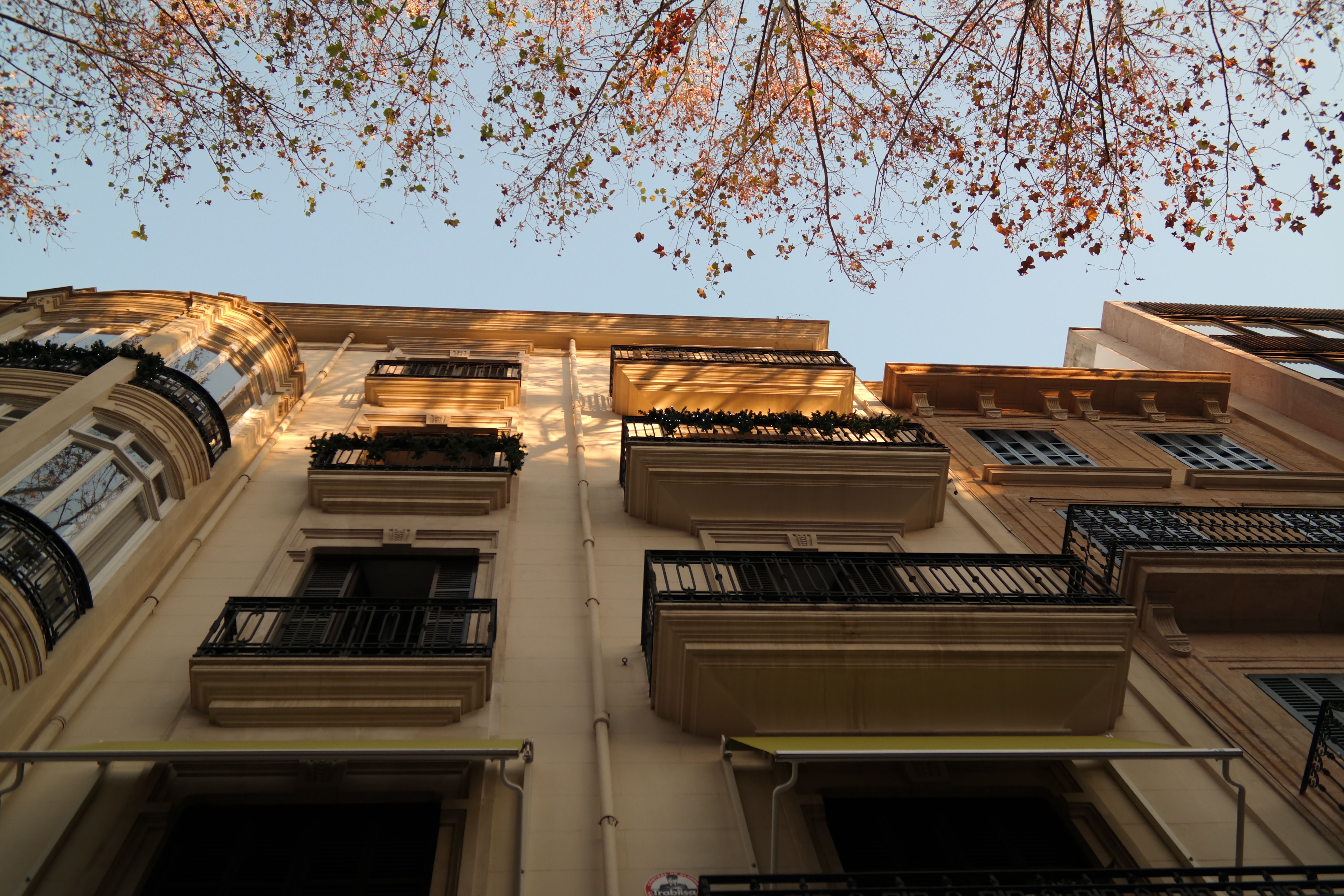 Low angle view of a classic Spanish building with balconies and blue sky.