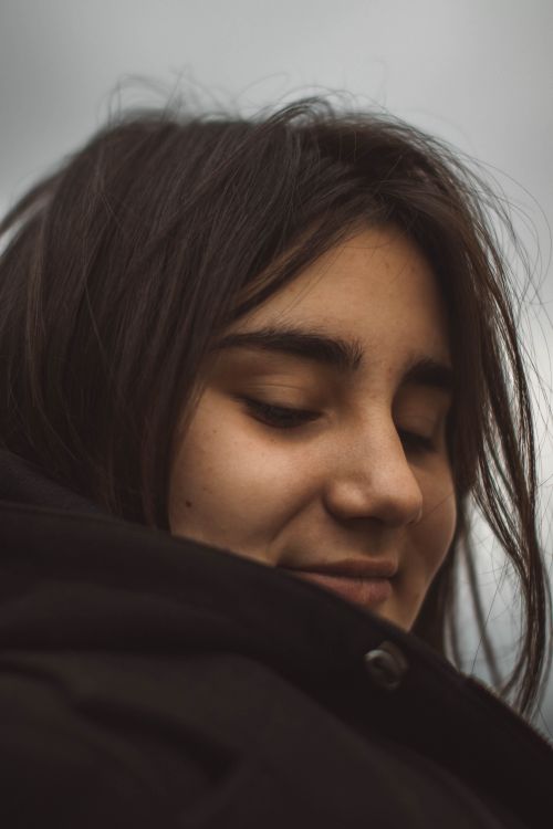 Free Close-up portrait of a woman with closed eyes in a warm coat, evoking a peaceful mood. Stock Photo