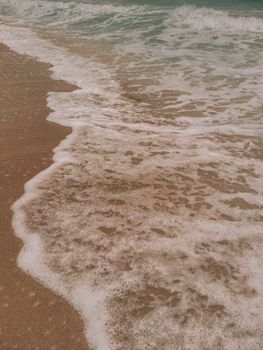 Relaxing view of gentle waves washing ashore a sandy beach under clear skies.