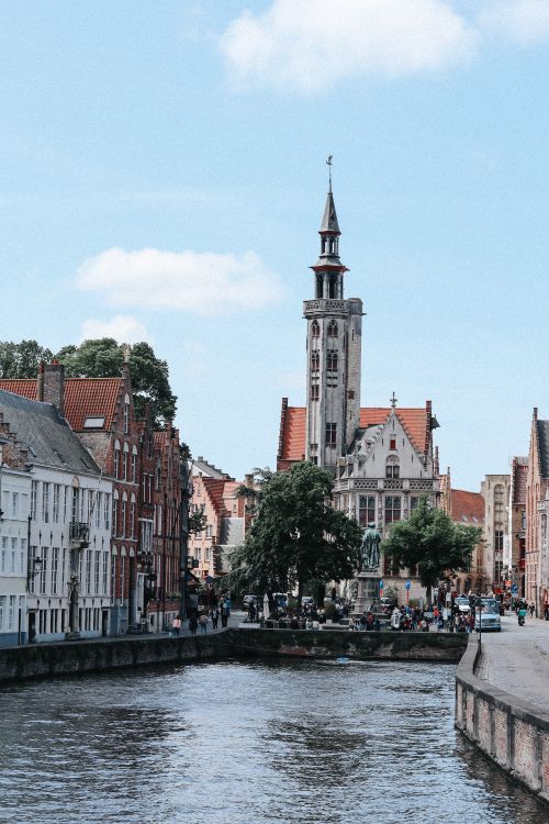 Free A picturesque cityscape of Bruges with canals and the iconic Poortersloge tower. Stock Photo