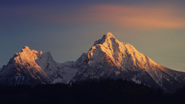 Breathtaking snowy mountain peaks illuminated by warm sunrise light, depicting natural beauty and serenity.