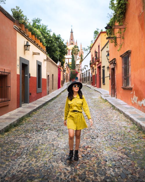 A Woman in a Yellow Coat Walking on Street
