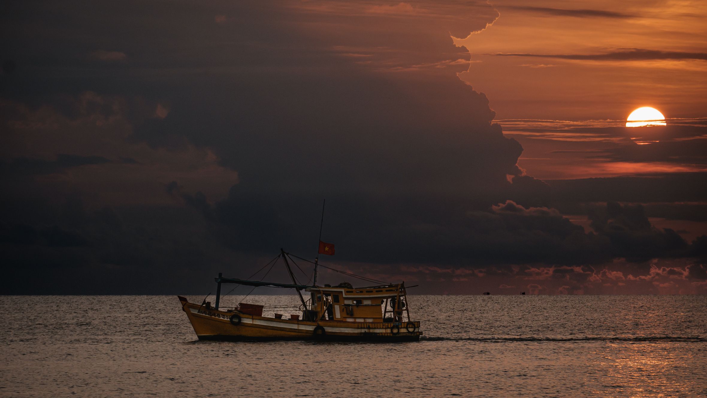A fishing boat sails on the sea at sunset, captured in Phu Quoc, Vietnam.