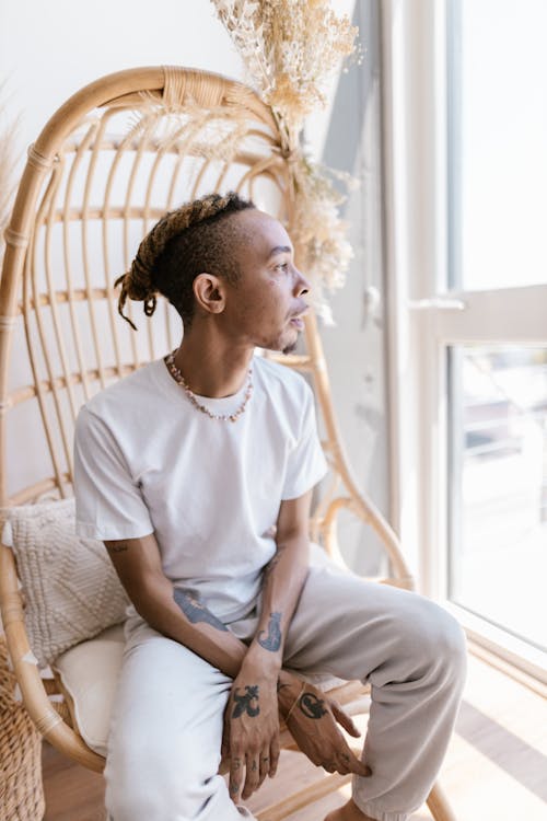  Man with Dreadlocks and Tattoos Sitting on a Basket Chair