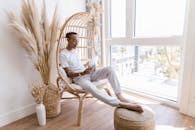 Woman in White Long Sleeve Shirt Sitting on Brown Wooden Chair