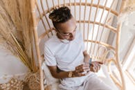 Man in White Crew Neck T-shirt Sitting on White Wooden Chair