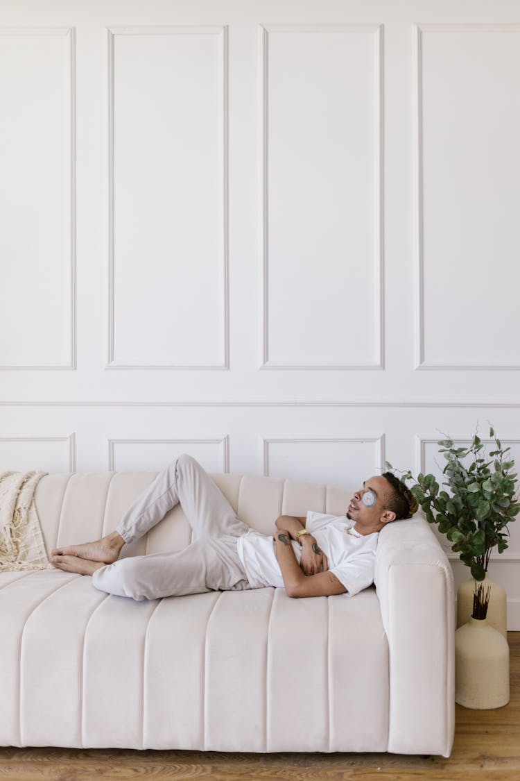 Man Lying Down On Sofa With Beauty Mask On Eyelids