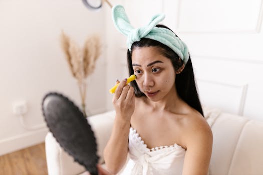 Young woman in a headband applying makeup in front of a mirror at home.