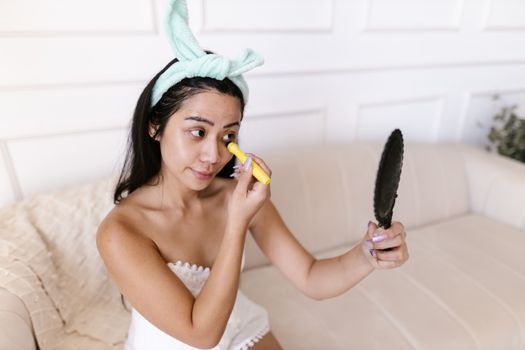 Woman with Hairband Applying Skin Corrector under Eyes