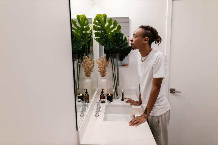 Man Looking In The Mirror In A Bathroom 