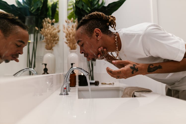 Man Washing Face At Bathroom Sink