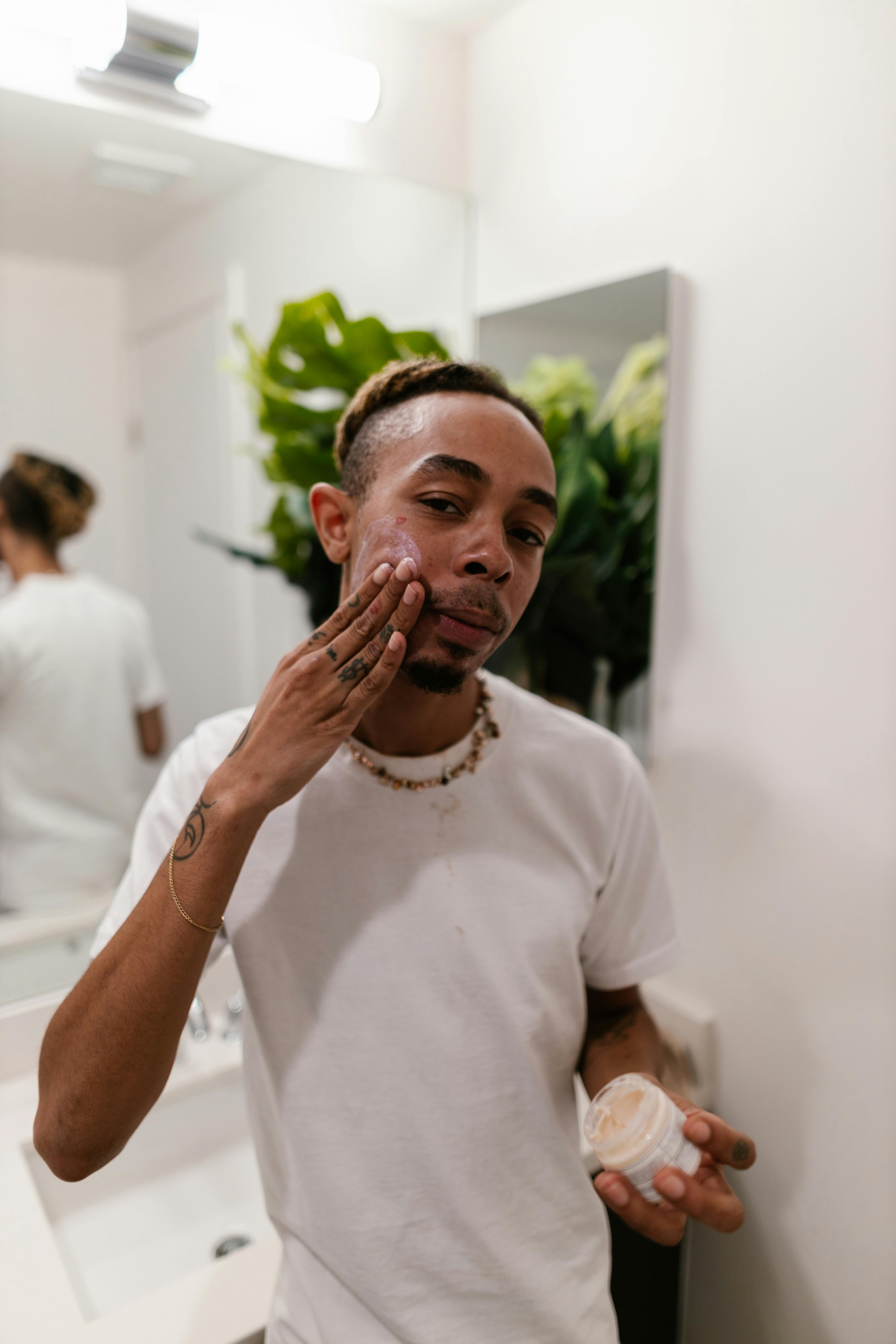 man in white a t shirt applying face cream