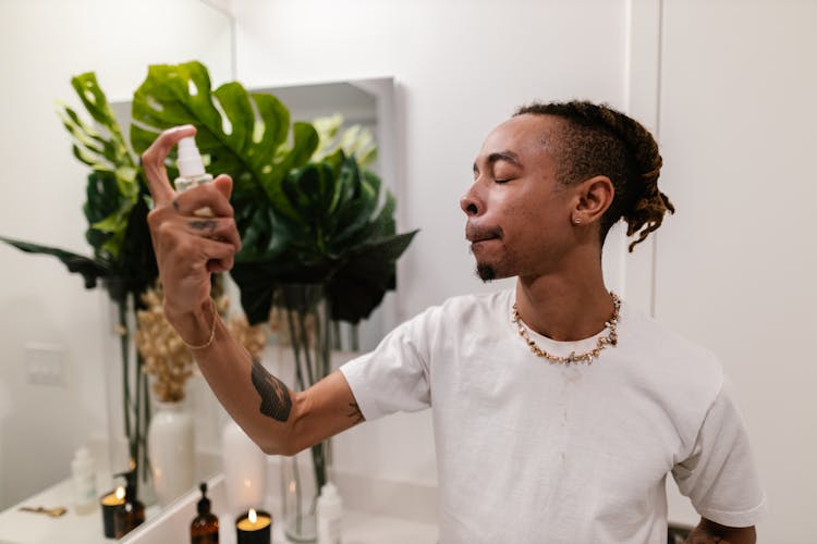 Young Man Applying Spray On Face