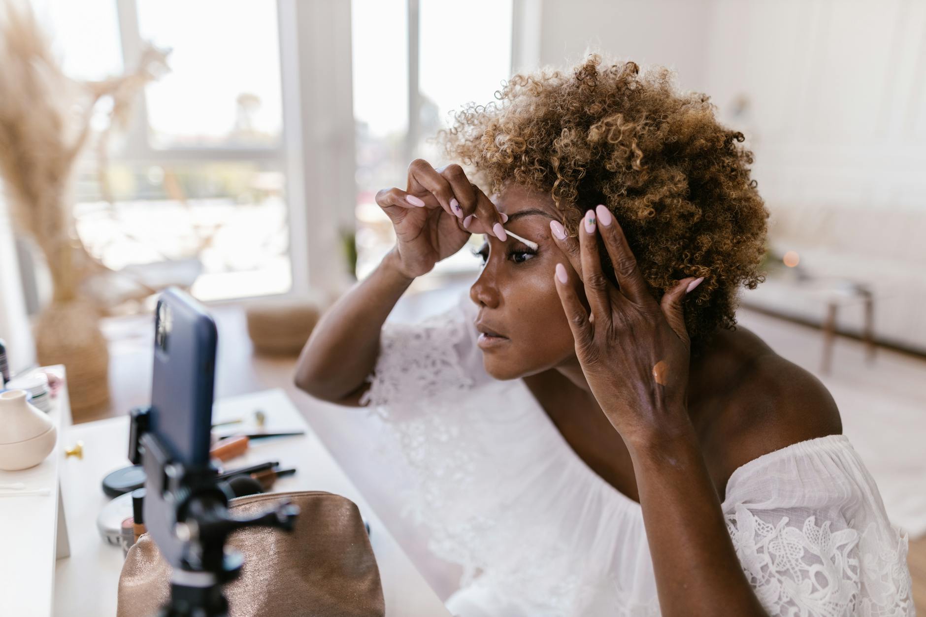 A makeup artist recording a tutorial on a smartphone indoors