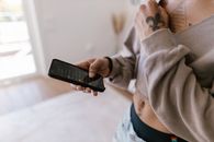 Person in Gray Sweater Holding Black Smartphone