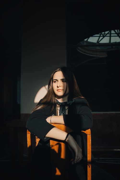 Free Elegant portrait of a woman seated indoors with dramatic sunlight highlighting her features. İzmir, Turkey. Stock Photo