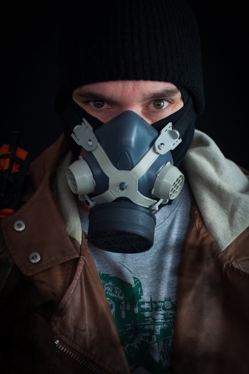 Man in Brown Leather Jacket Wearing Black and Gray Gas Mask