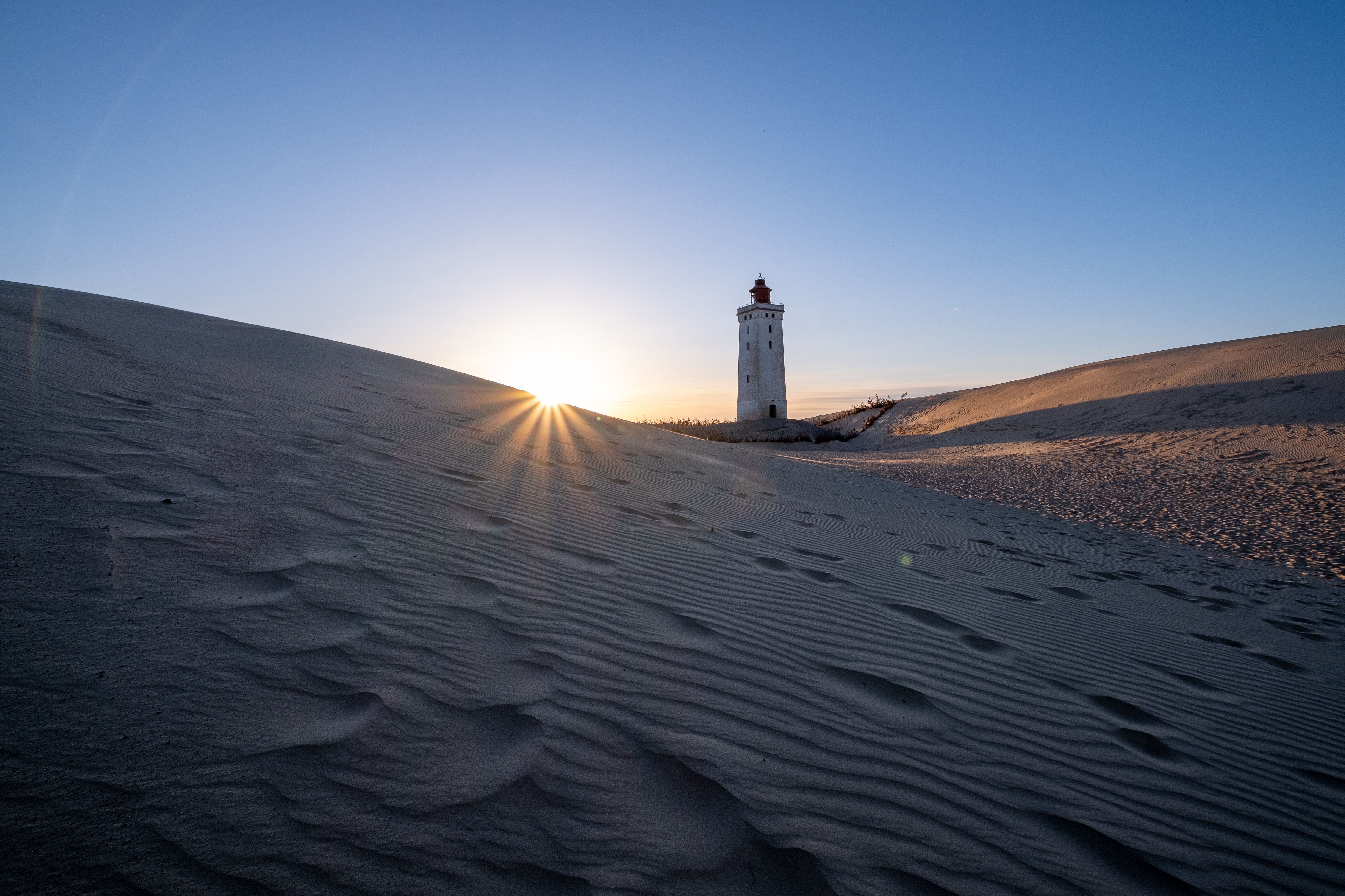 Beautiful sunset over sand dunes with Rubjerg Knude Lighthouse in Denmark.