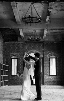 A couple dances gracefully in a rustic venue, capturing a timeless wedding moment.