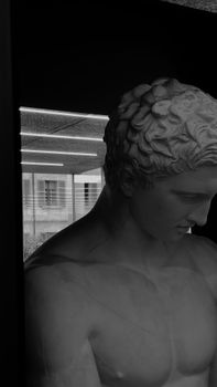 Black and white close-up of a marble statue on display in a Milan window.