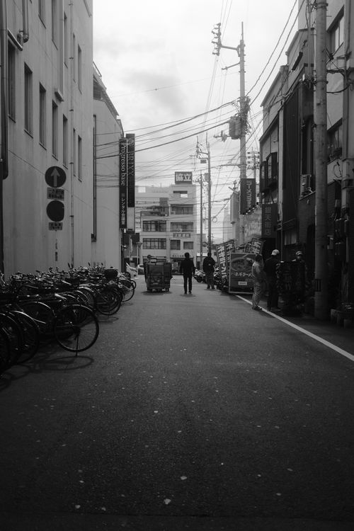 Free A black and white urban street scene featuring bicycles, buildings, and people. Stock Photo
