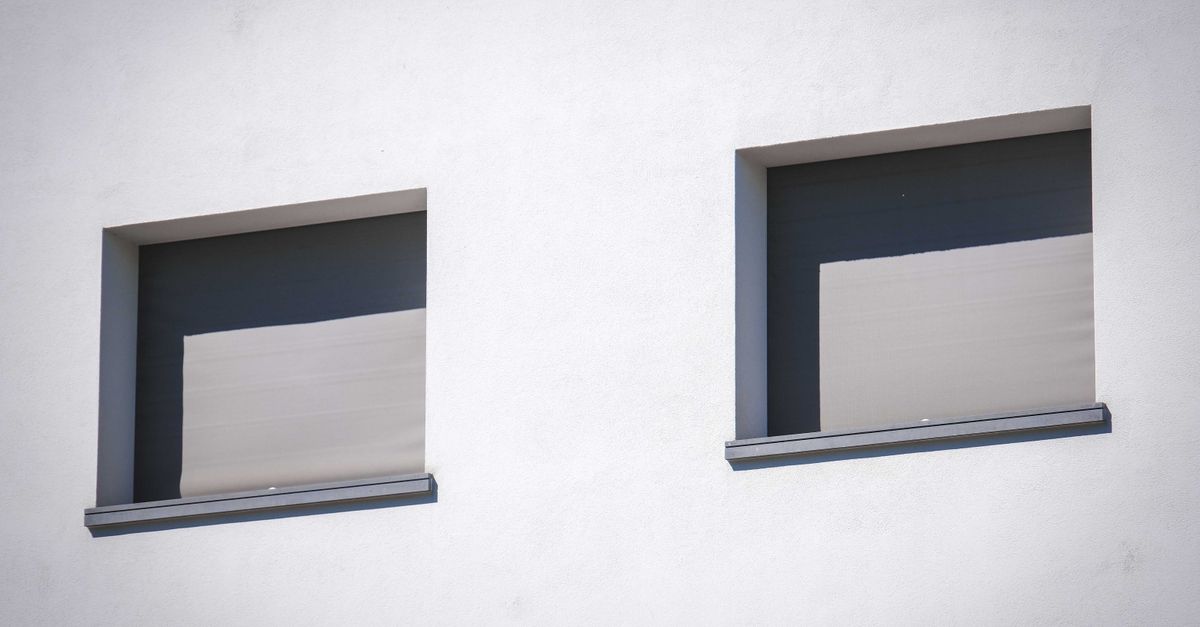 Nahaufnahme einer weißen Wand mit zwei sonnenbeschienenen Fenstern im minimalistischen Stil