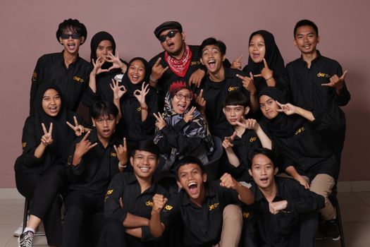 Happy group of teenagers making hand signs and posing for a fun indoor group portrait. - Fotografer Sidoarjo