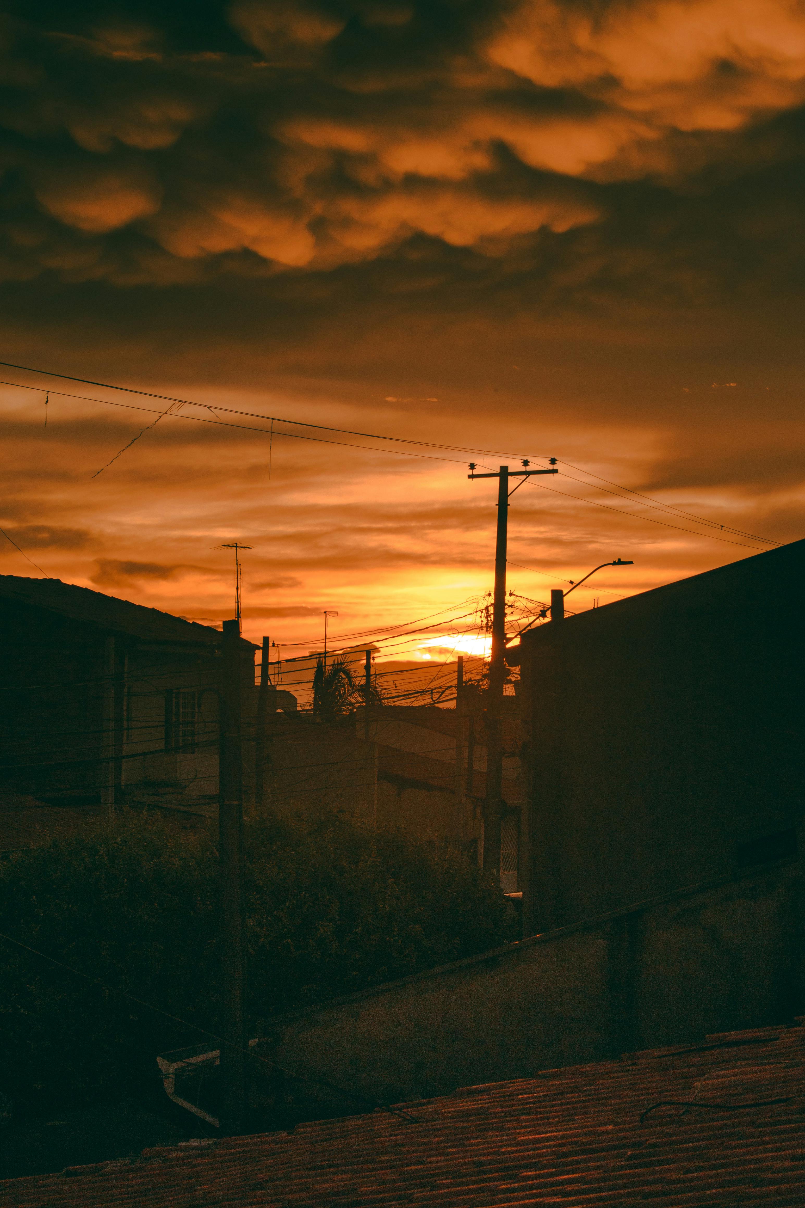 Backlit urban sunset in São Paulo suburb with dramatic sky and building silhouettes.