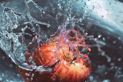 Free Vivid close-up of an apple making a splash in water, showcasing bright colors and dynamic motion. Stock Photo